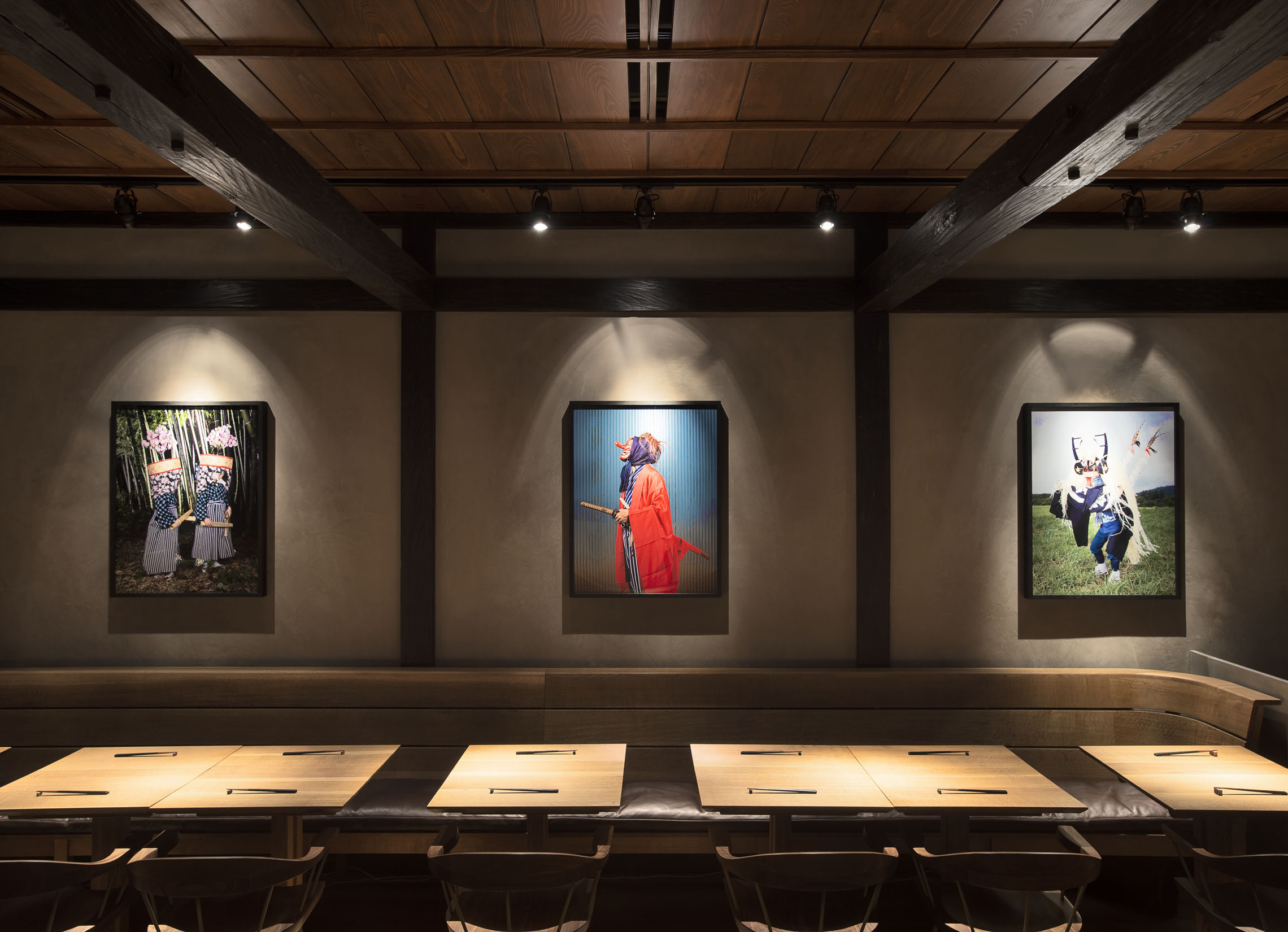 The dining room at Hiroki Omakase Philadelphia featuring large framed photographs of Japanese ceremonial figures mounted on textured plaster walls.