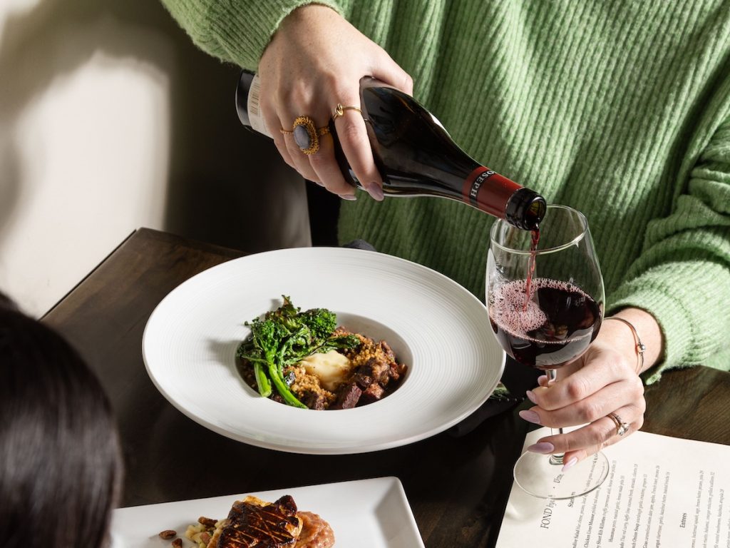 Fond wine pairing dinner pouring red wine over a plated entree at the East Passyunk BYOB